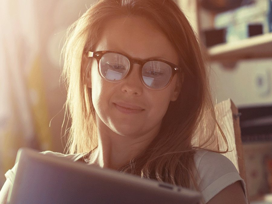 Woman wearing blue light glasses using an ipad