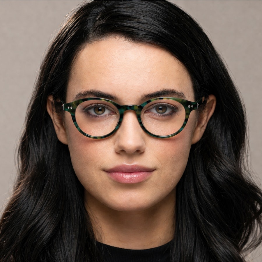 Woman wearing a green mottled round plastic glasses frame
