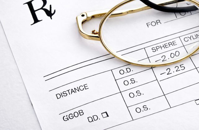 Gold metal glasses laying flat on a glasses prescription