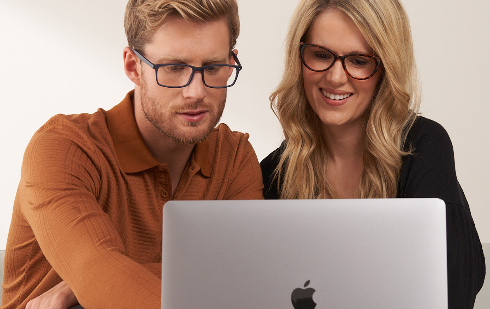 Man and woman both wearing glasses looking at a laptop