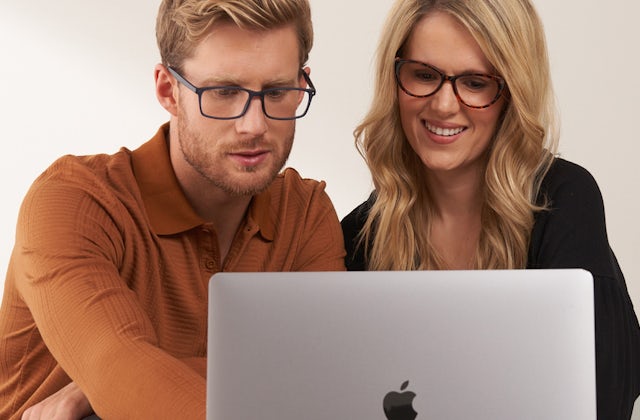 Man and woman both wearing glasses looking at a laptop