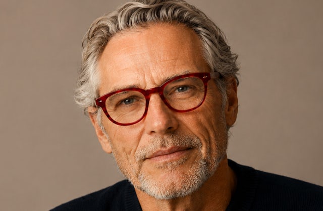 Older man with grey hair wearing red plastic frames