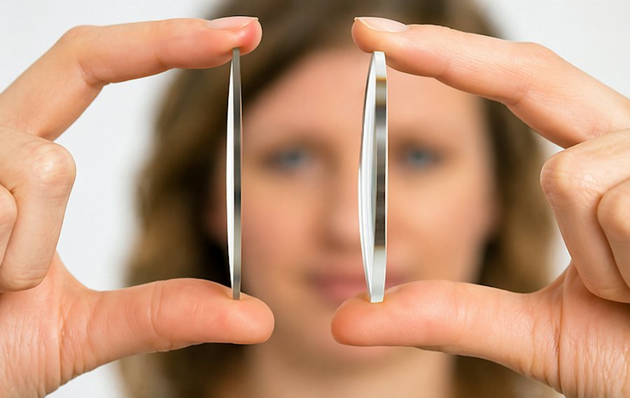 Woman holding two optical lenses highlighting the difference between standard thickness and high index lenses