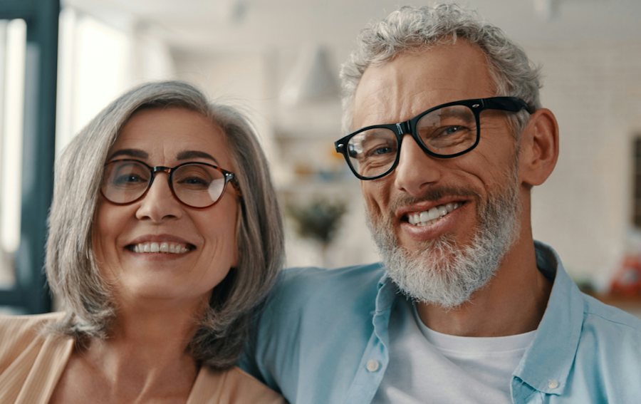 Man and woman sat together smiling both wearing glasses