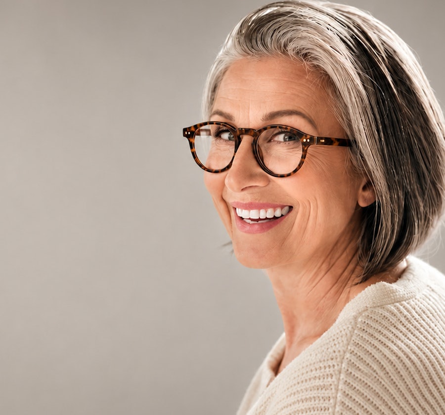 Attactive older lady with bobbed grey hear smiling wearing round havana glasses