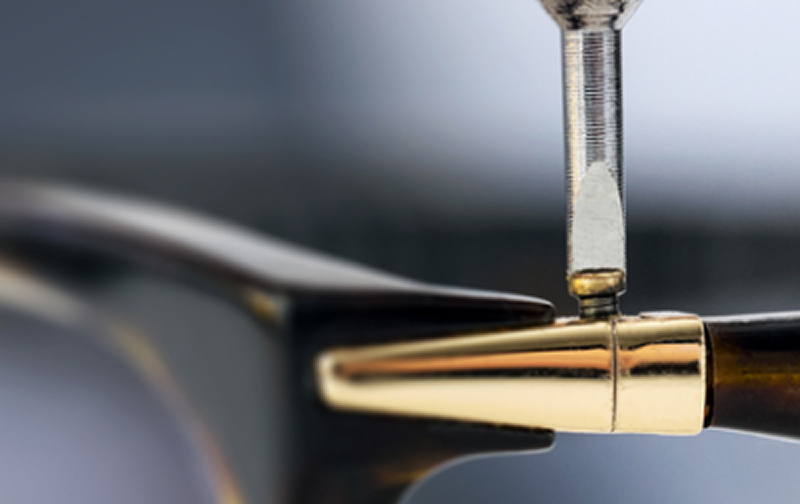 Screwdriver adjusting the screw on the hinge of a glasses frame