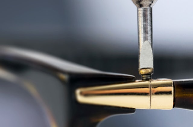 Screwdriver adjusting the screw on the hinge of a glasses frame