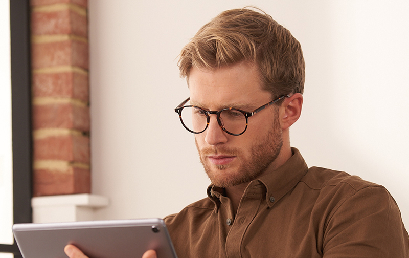 Man wearing glasses looking at an ipad