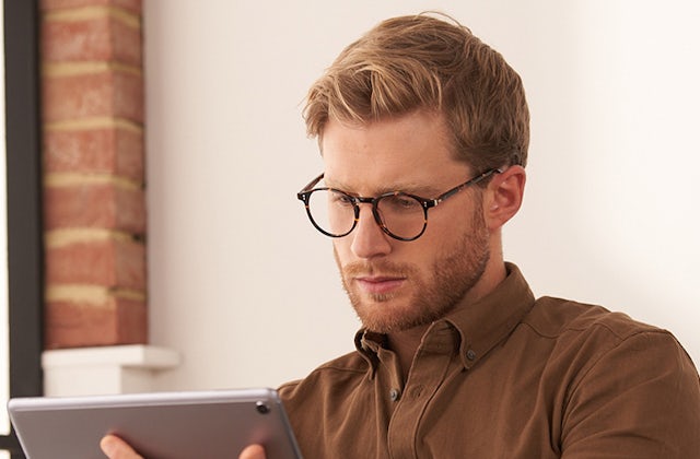 Man wearing glasses looking at an ipad