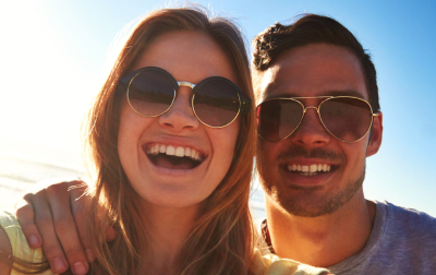 Attractive couple wearing sunglasses smiling into the camera