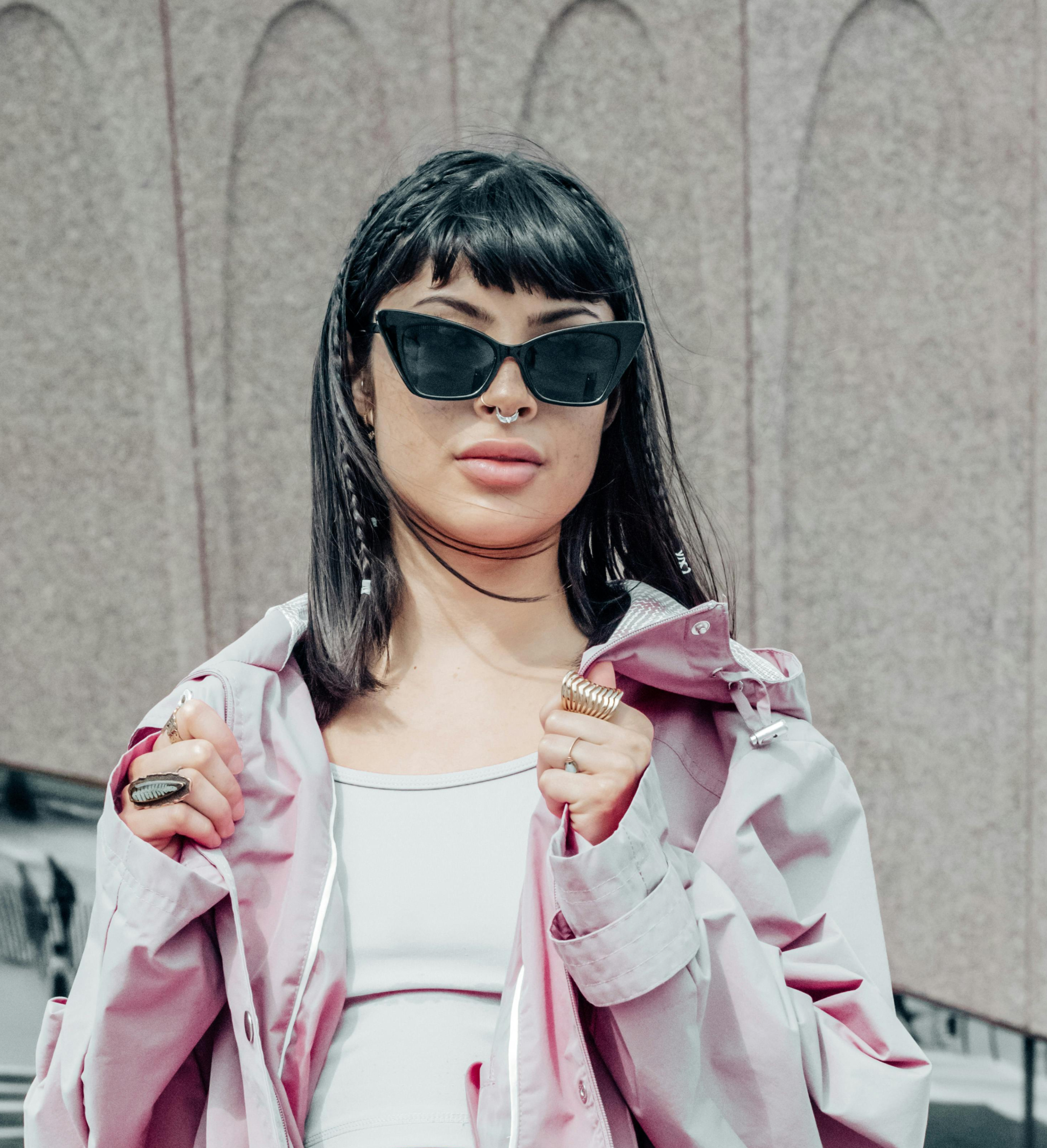 Woman in a pink jacket wearing black cat eye shaped sunglasses