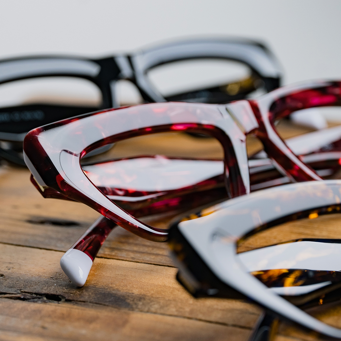 Row of different coloured cat eye shaped frames on a wooden table