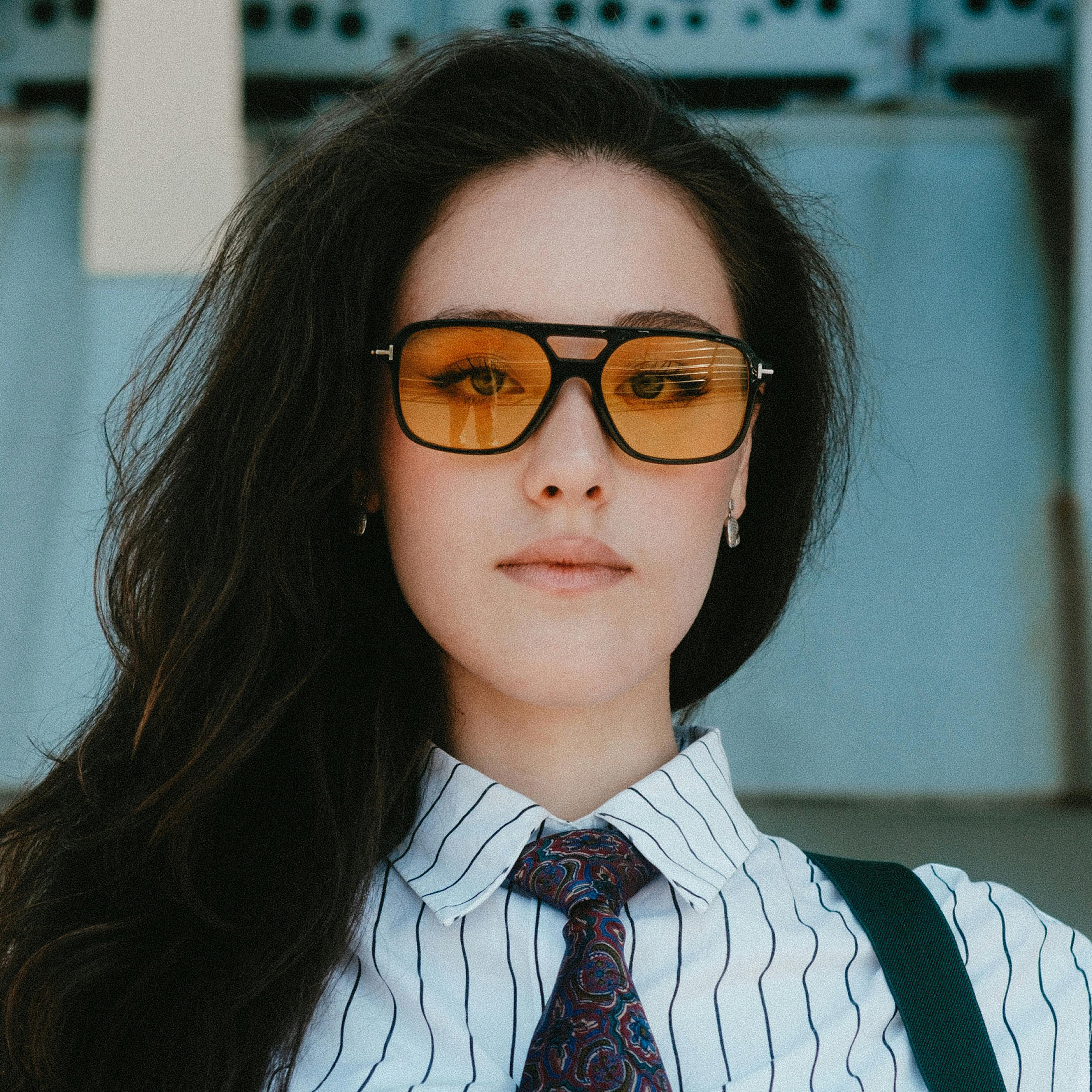 Woman wearing aviator inspired black plastic glasses with amber tinted lenses