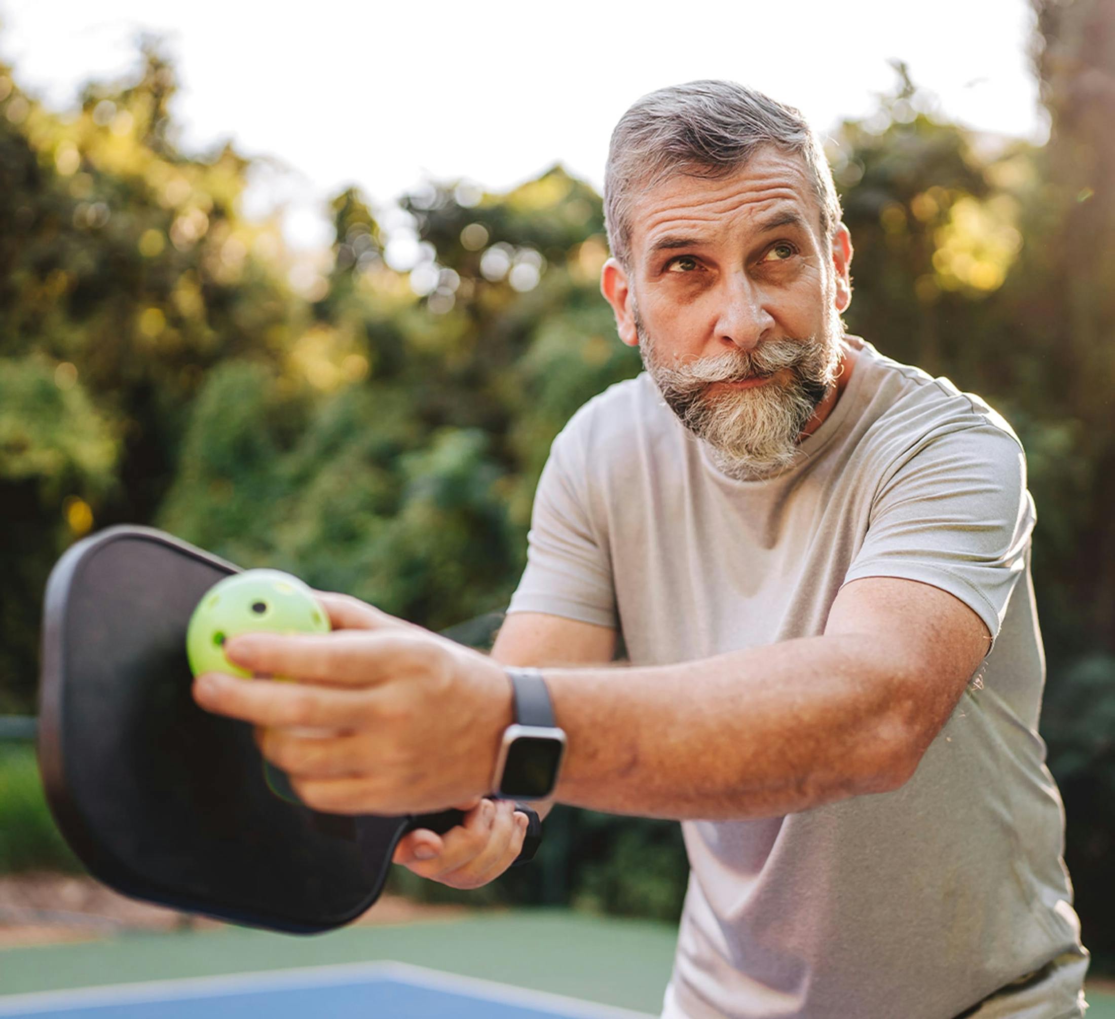 Man holding pickleball and racket