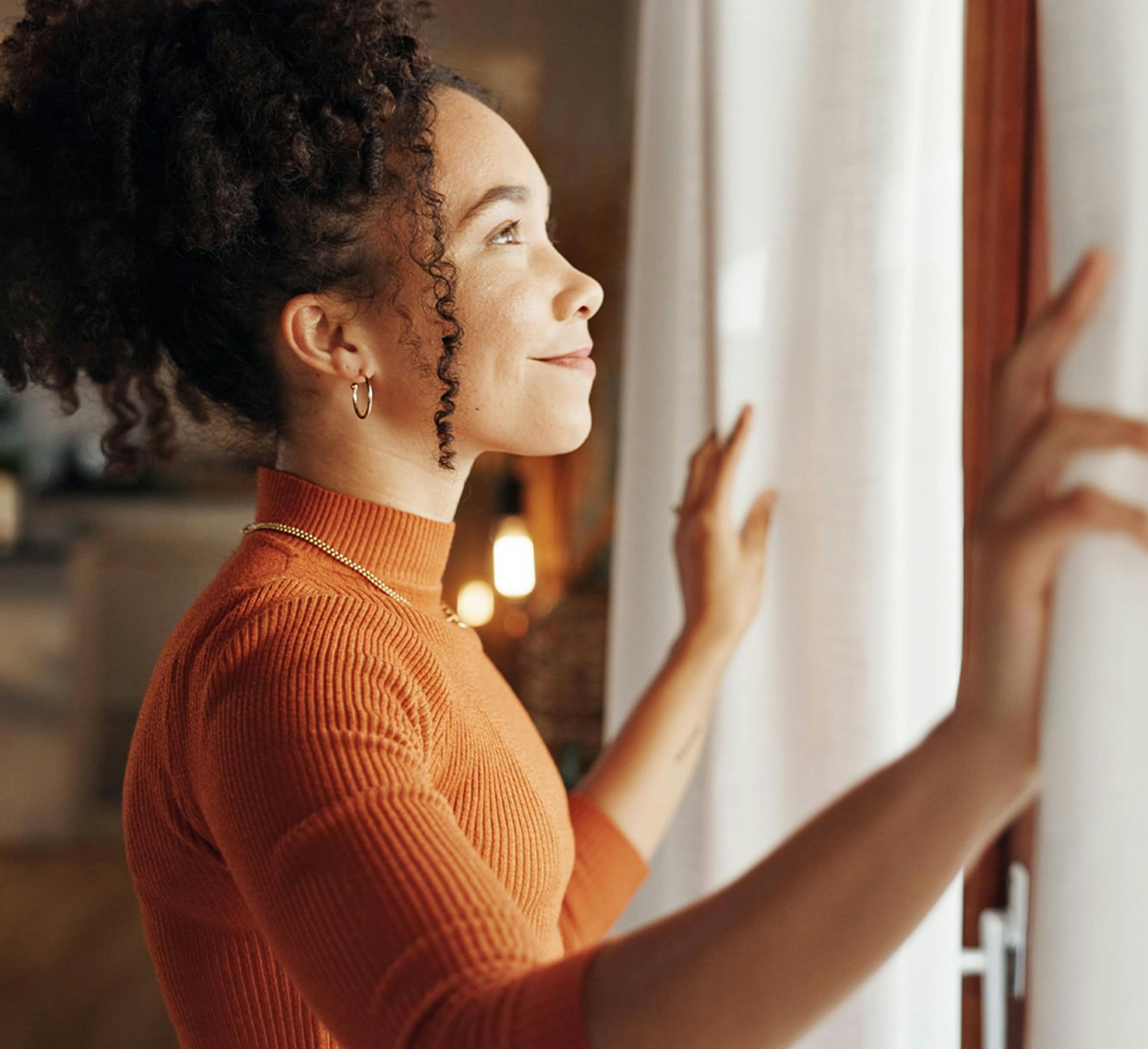woman opening up the curtains to a window