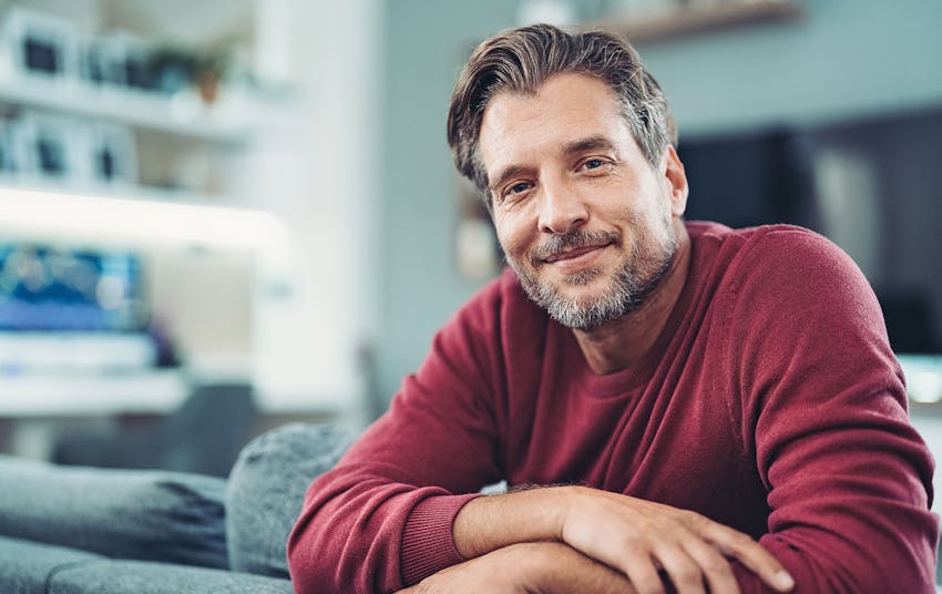 man smiling while leaning on couch head rest