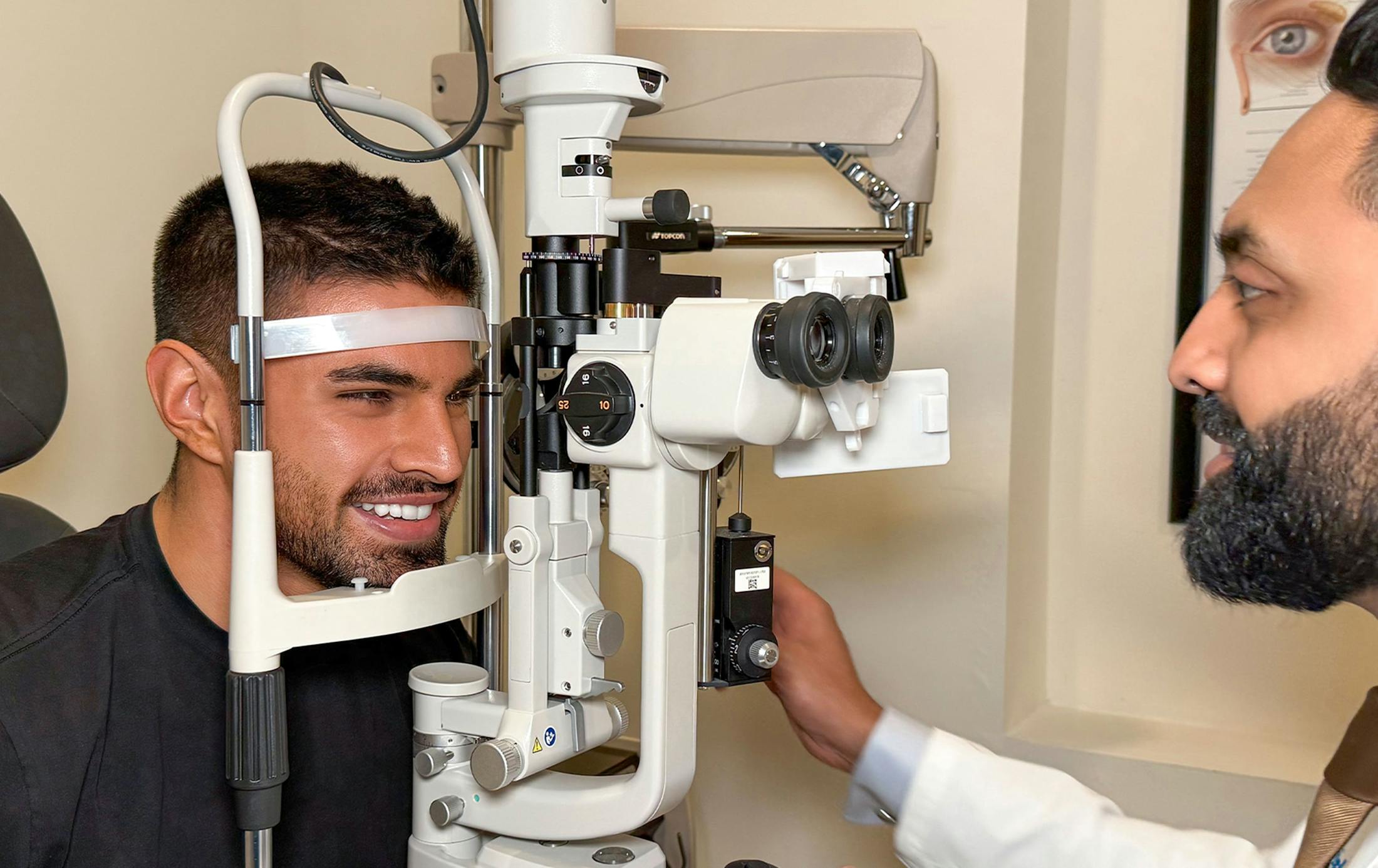 man smiling while getting his eyes checked by doctor