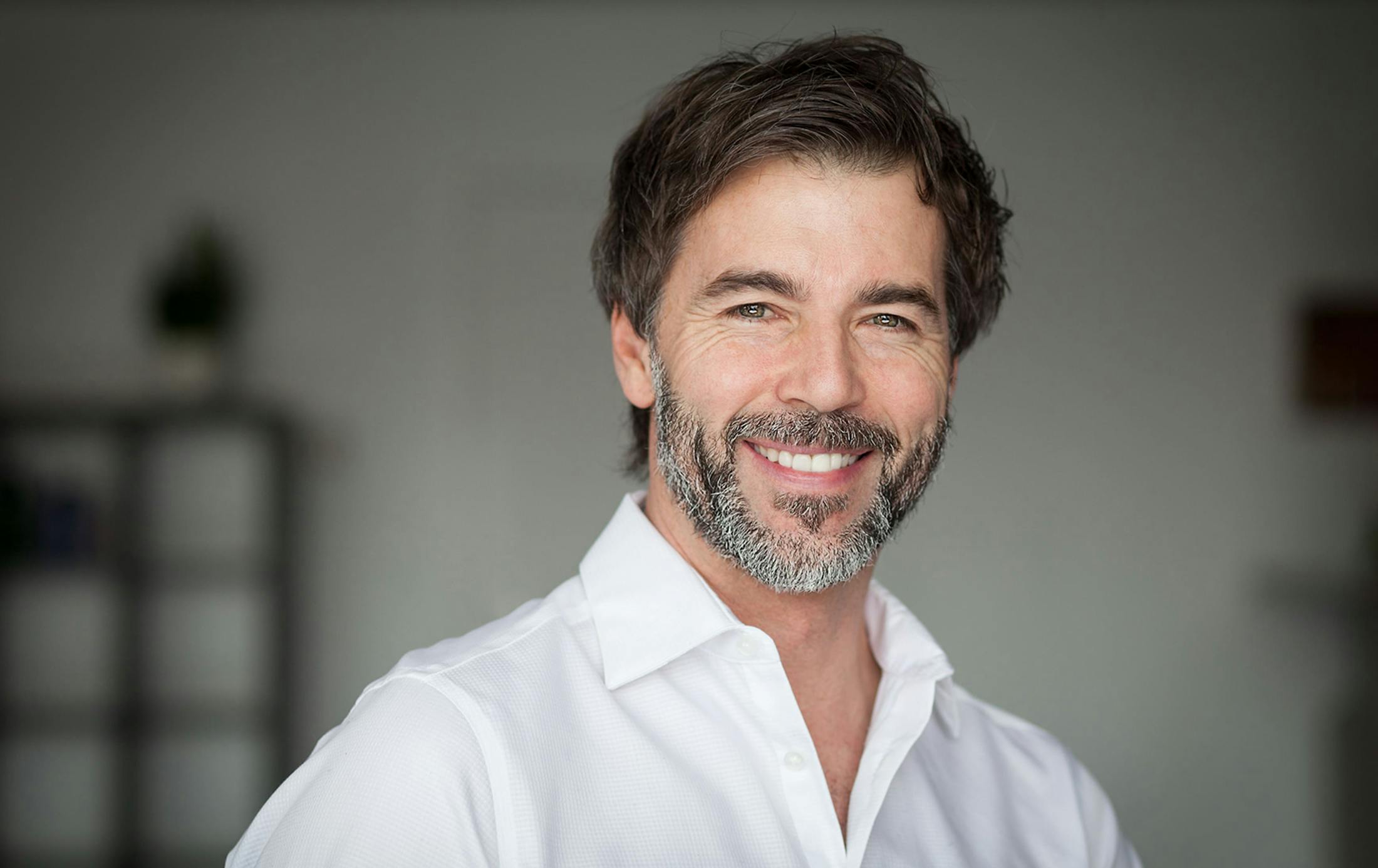 man smiling forward wearing a white shirt