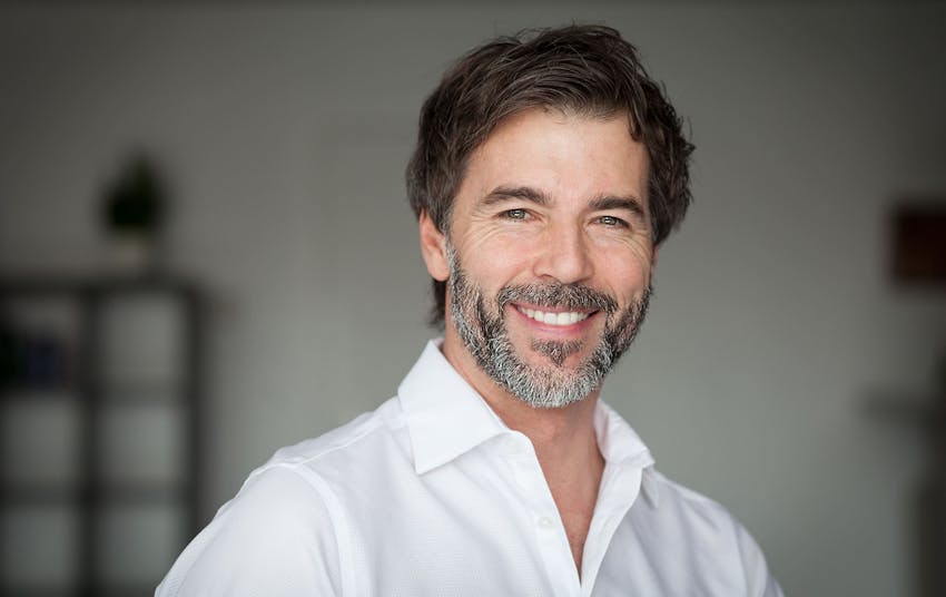 man smiling forward wearing a white shirt