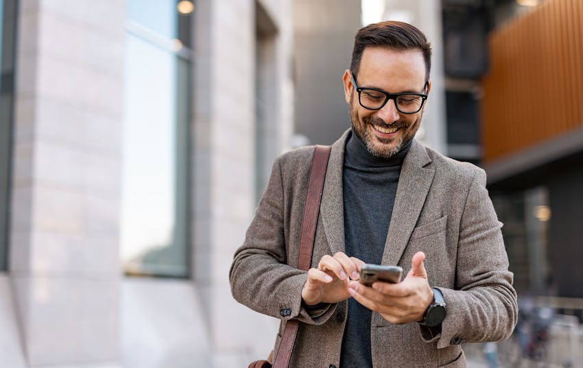 man smiling on his phone outside