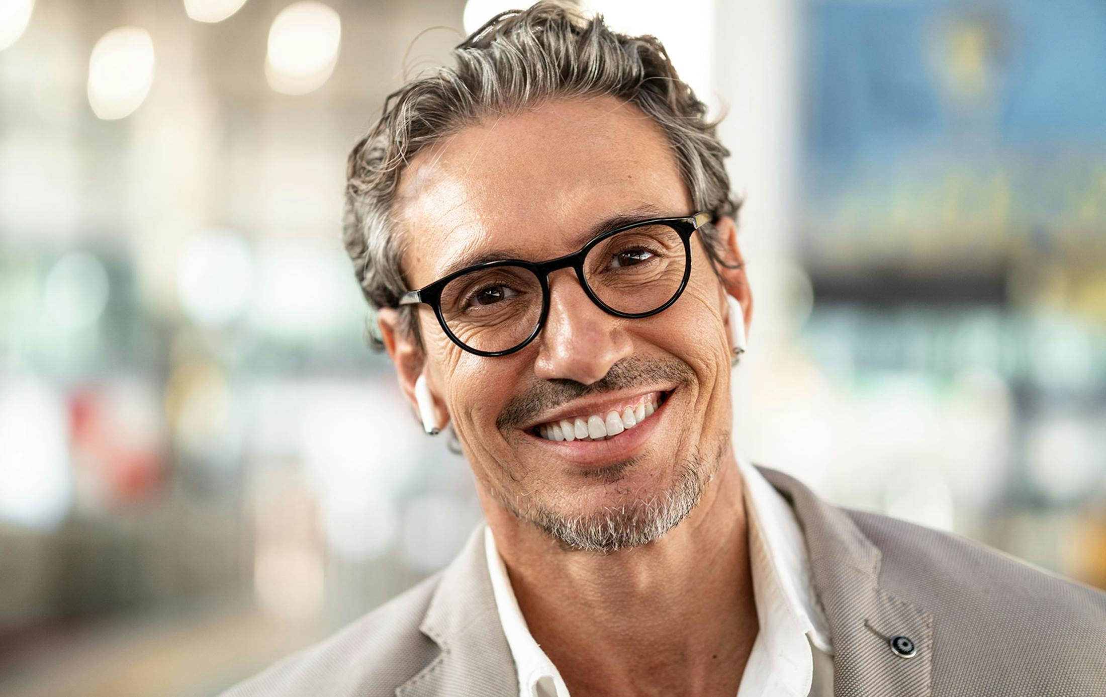 man smiling with glasses on and airpods in his ears