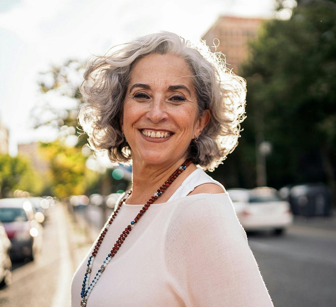 older woman smiling on the sidewalk