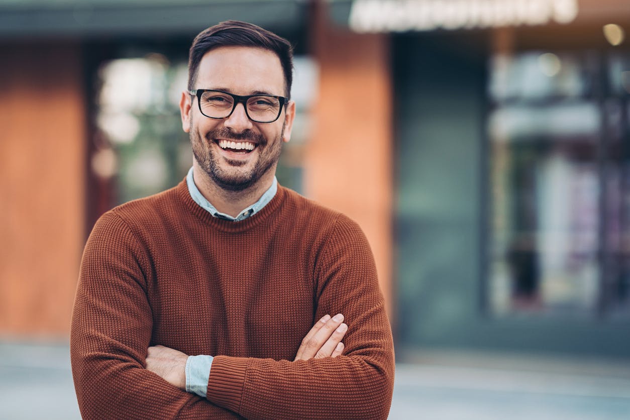 man smiling in a dark orange sweater
