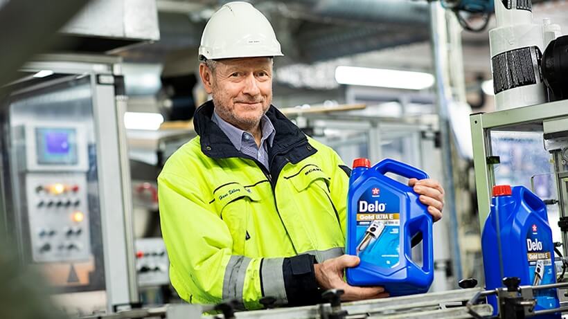 En man som håller en blå förpackning med delo smörjmedel