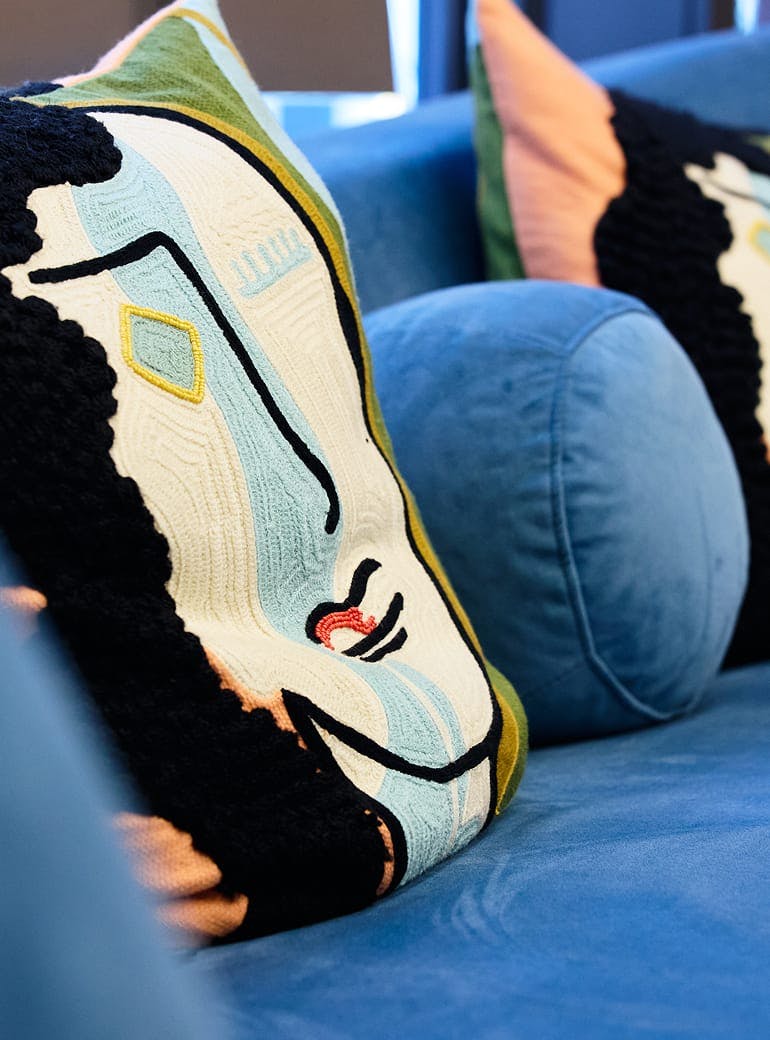 artistic pillow on a blue couch