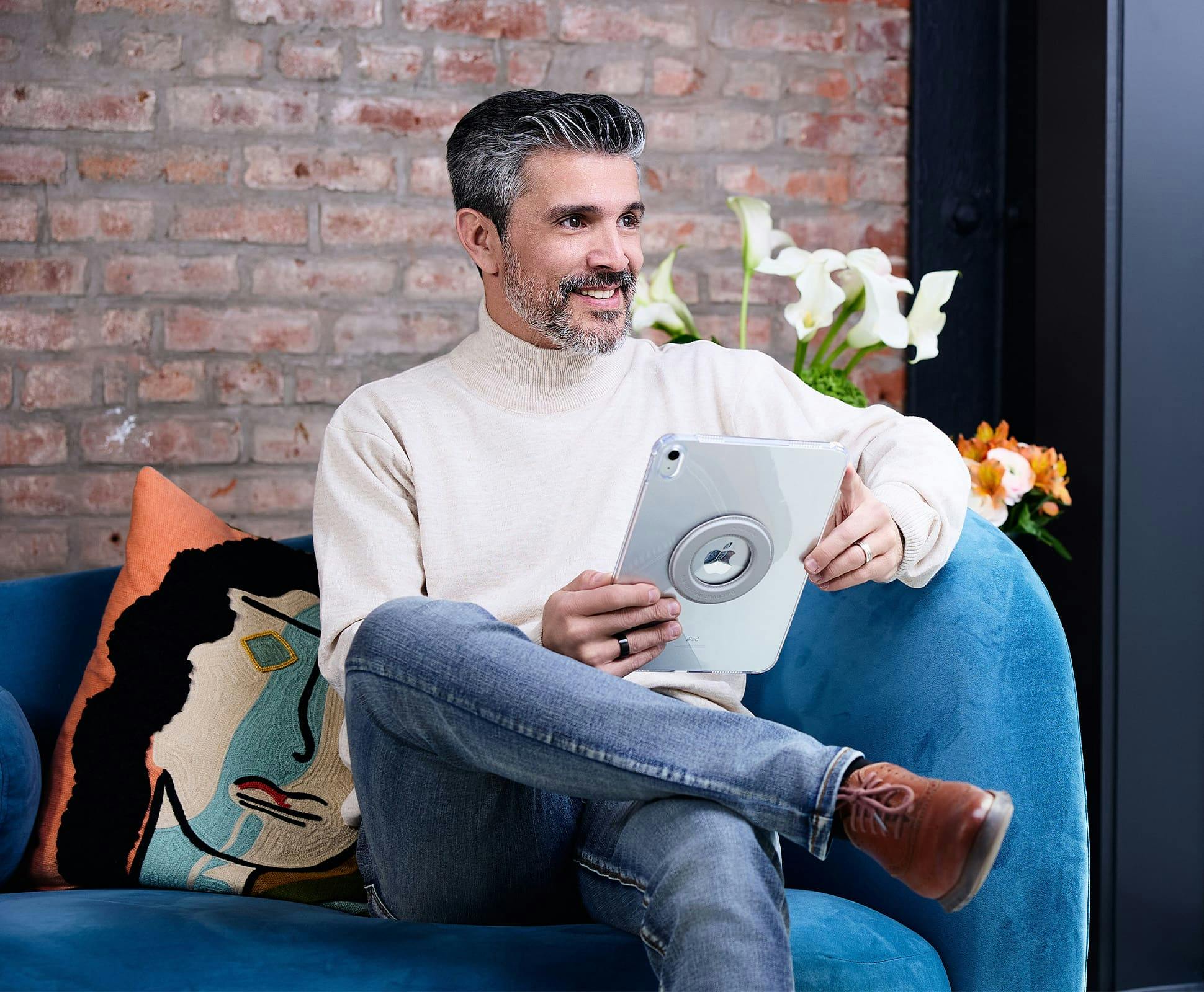 man sitting on couch with ipad in hand and smiling