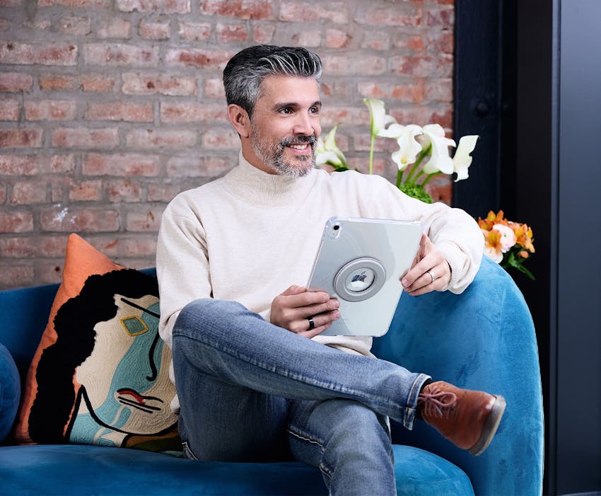 man sitting on couch with ipad in hand and smiling