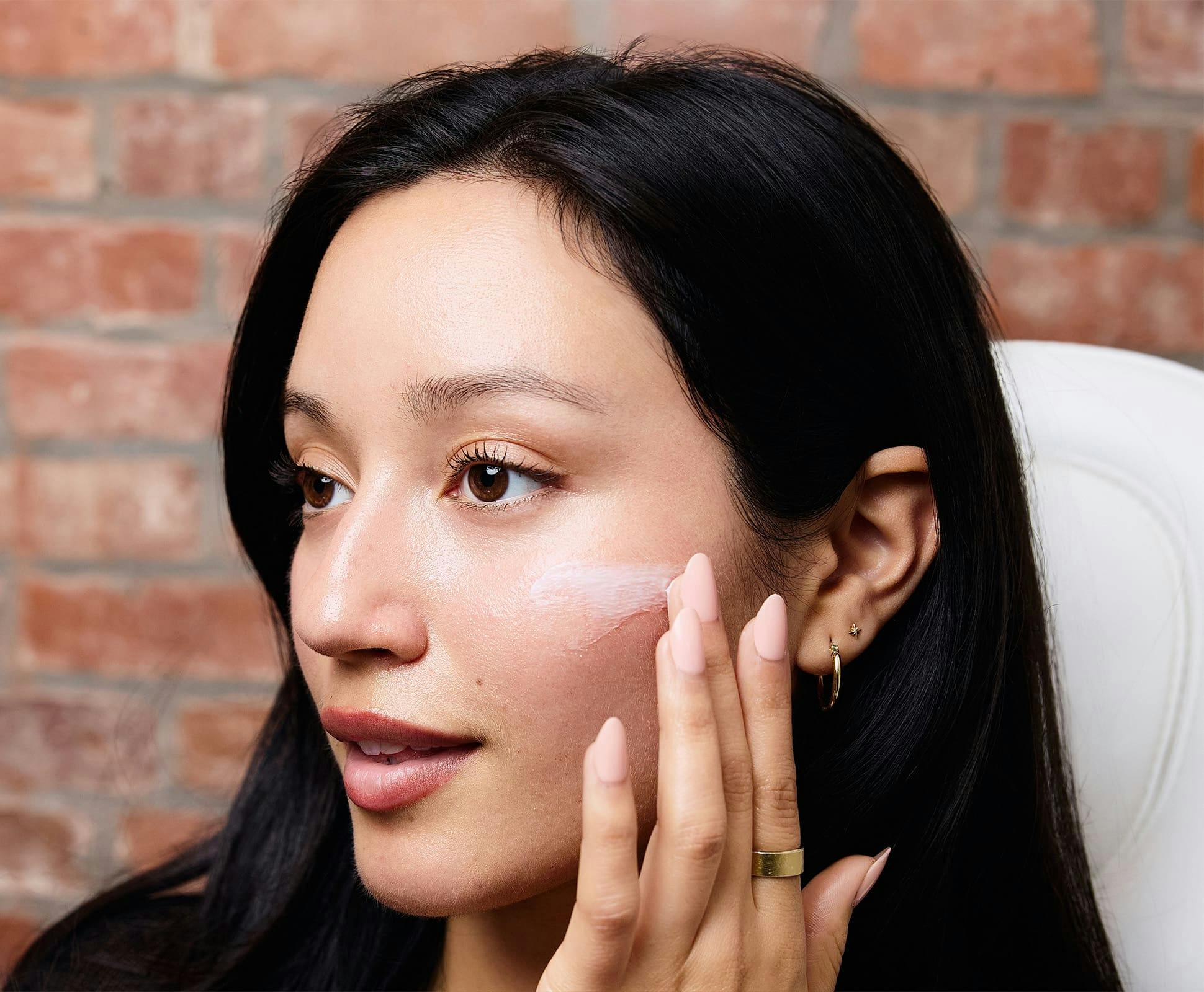 close up of woman applying skincare on her cheek