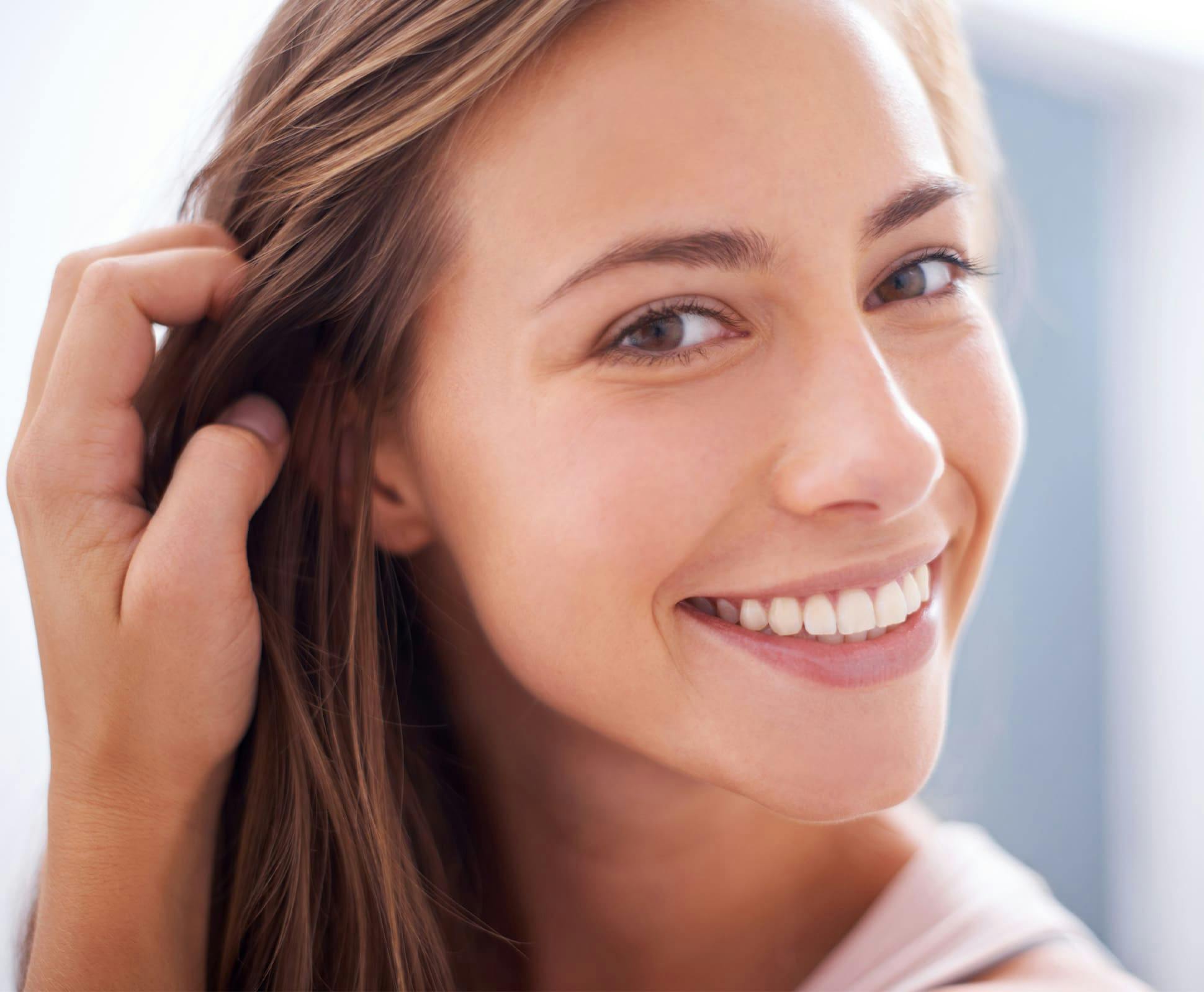 woman moving her hair out of the way and smiling