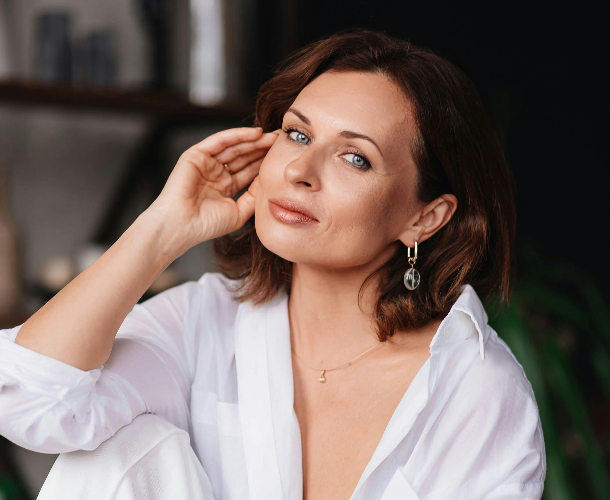 woman with short brown hair with her hand up to her face