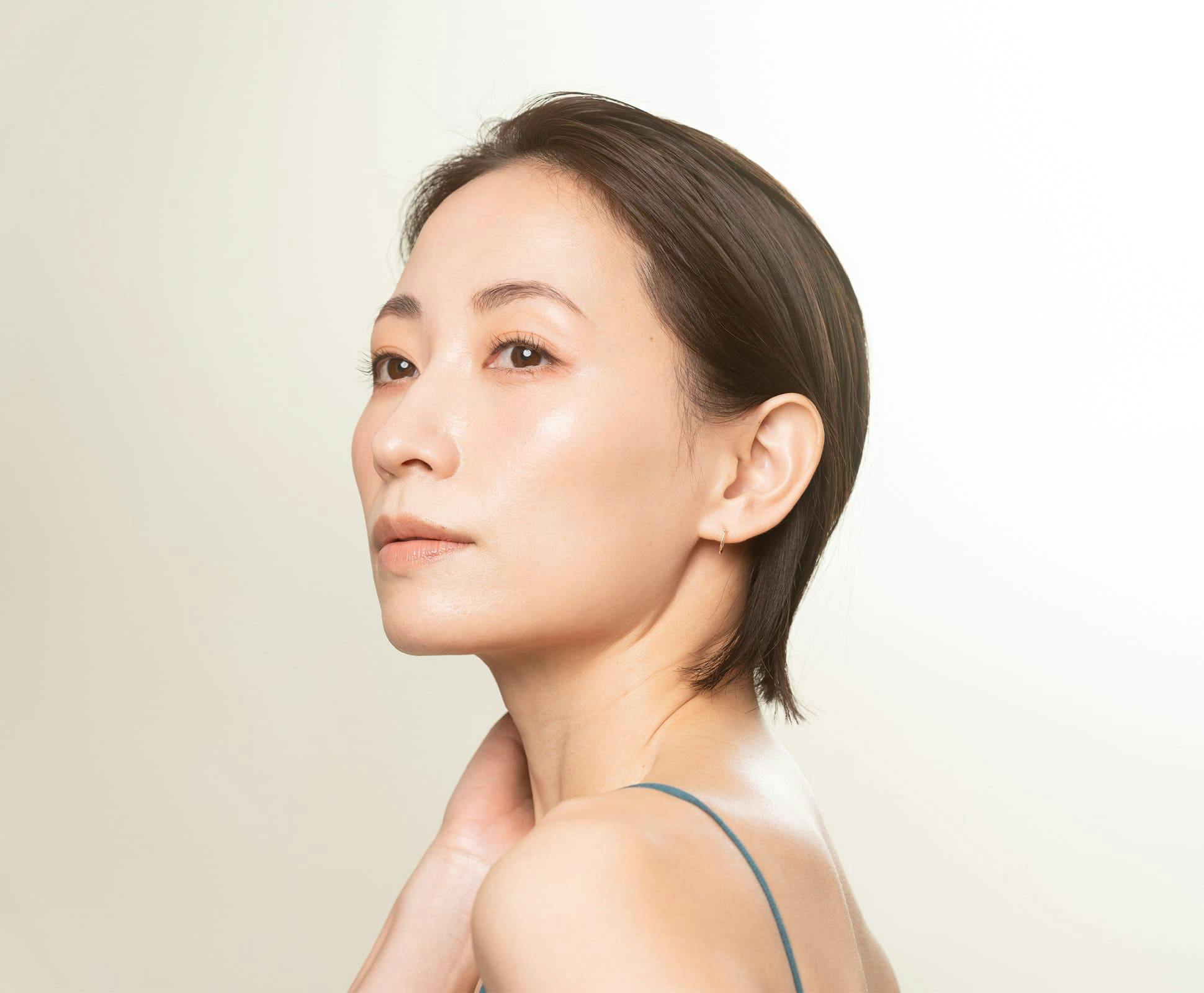 woman with short hair looking out while her hand touches her neck