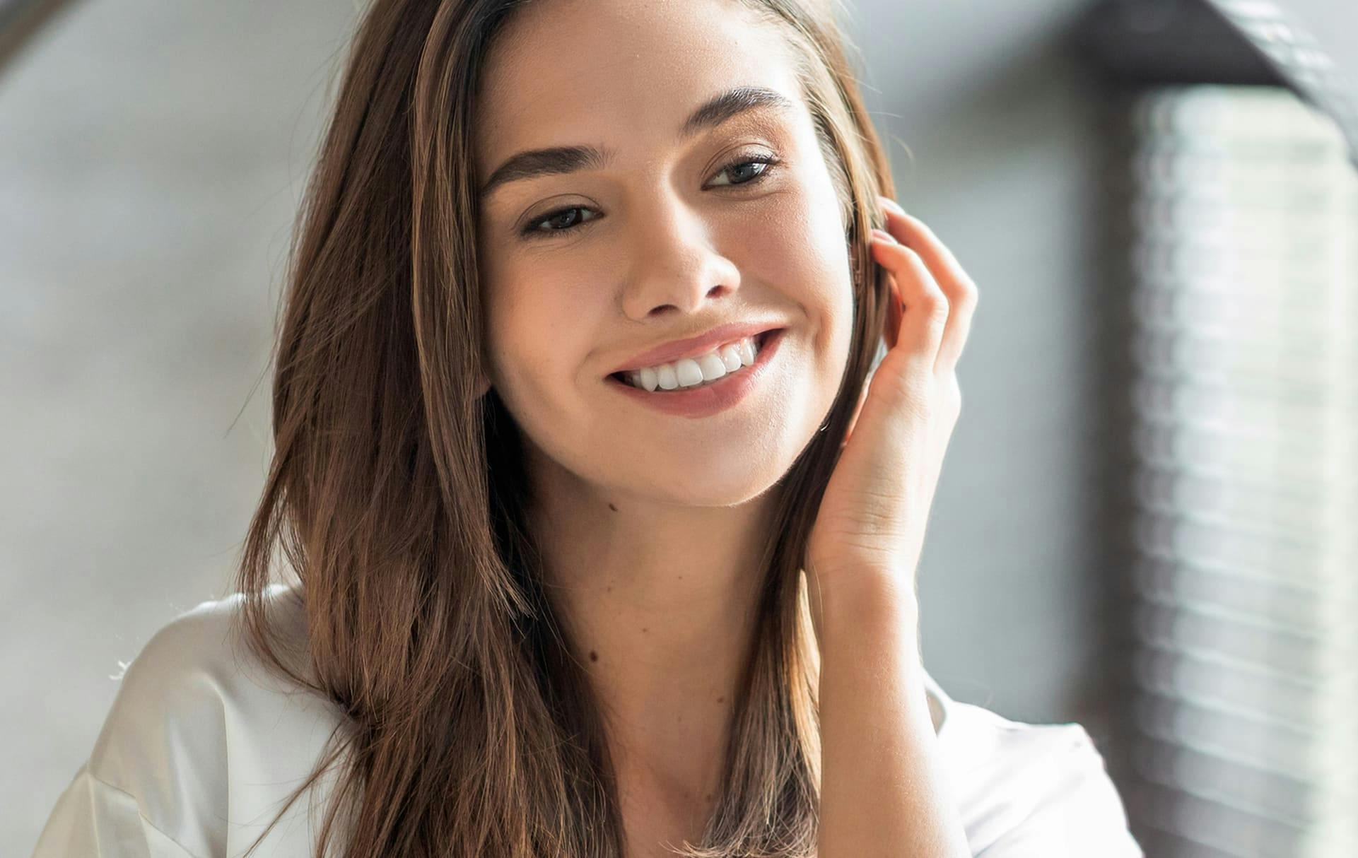 Woman smiling with hand up near ears