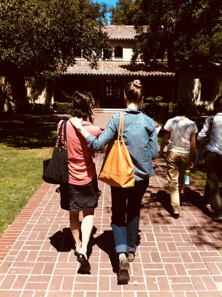 Two girls walking together away from the camera along a brick path