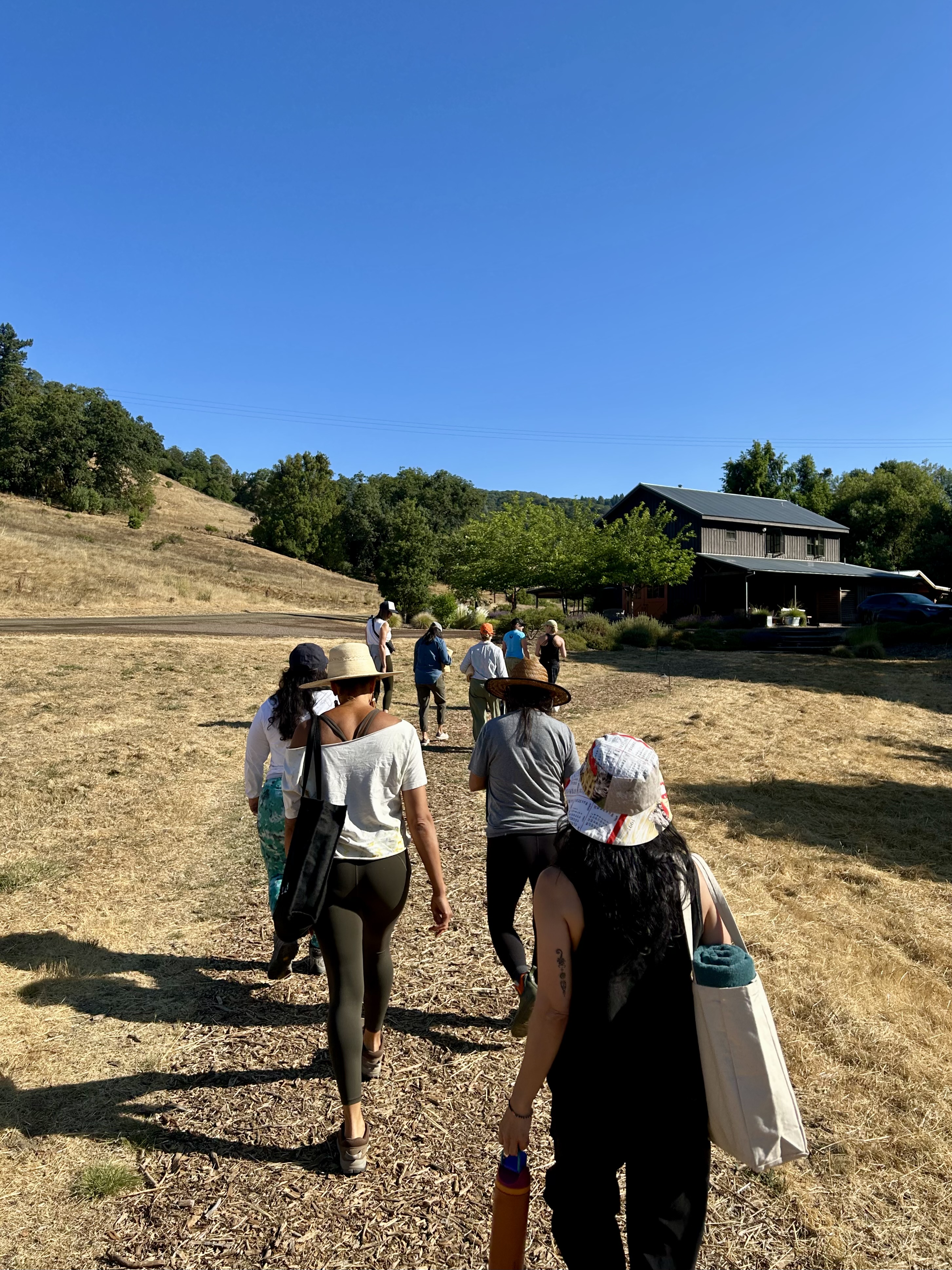 A group of people walking toward a building in a dry grassy field