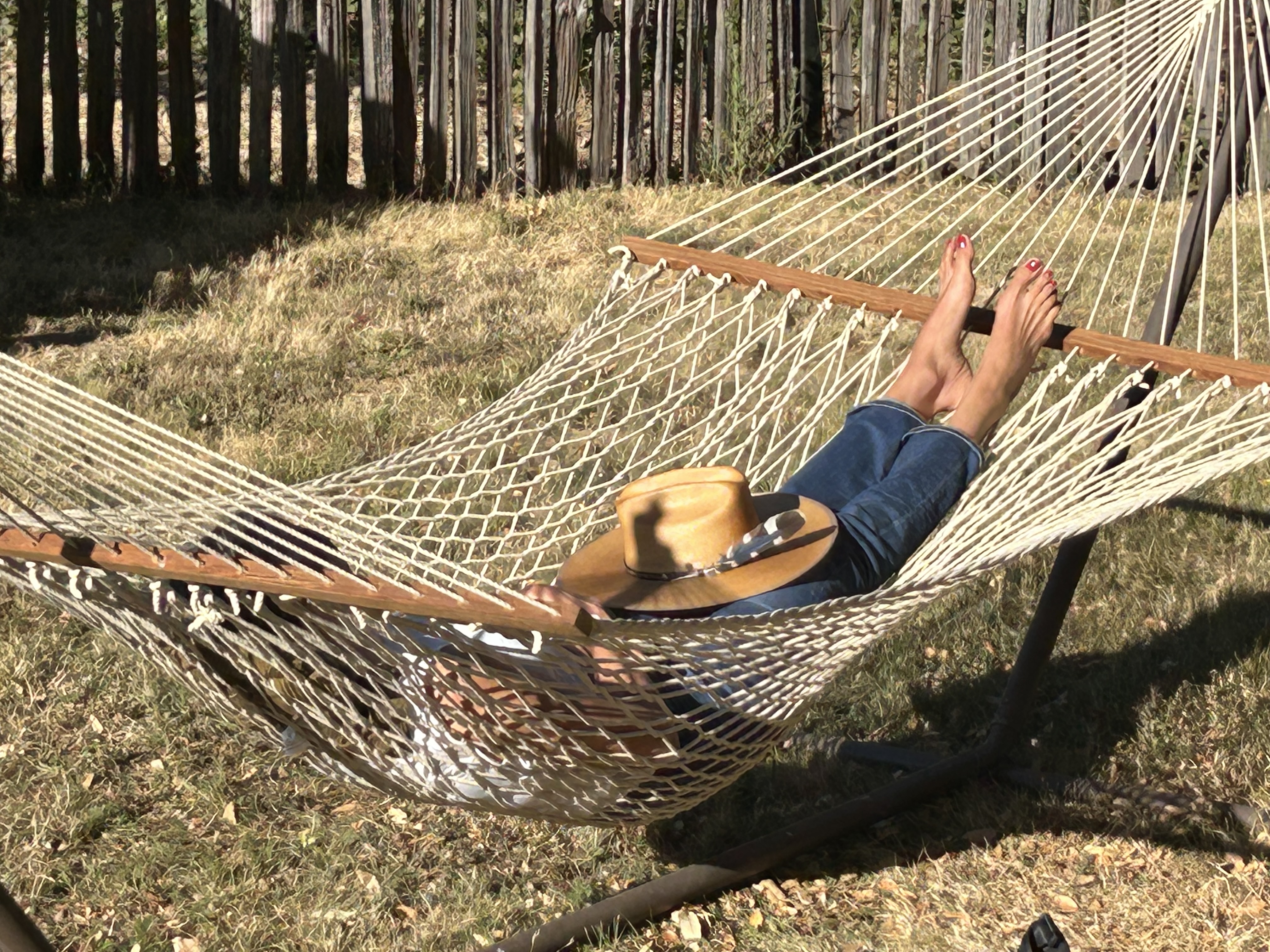 Person sleeping in a hammock with a hat on their lap