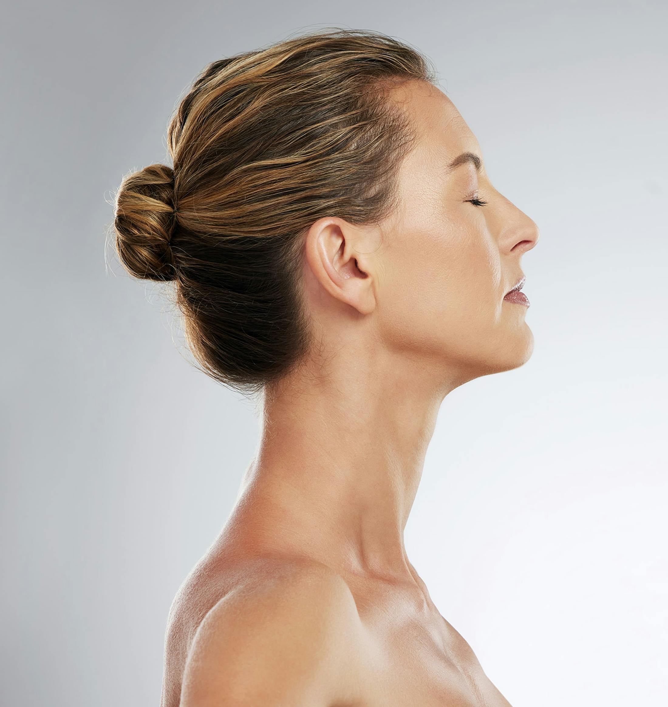woman facing the right with her eyes closed and hair in a bun