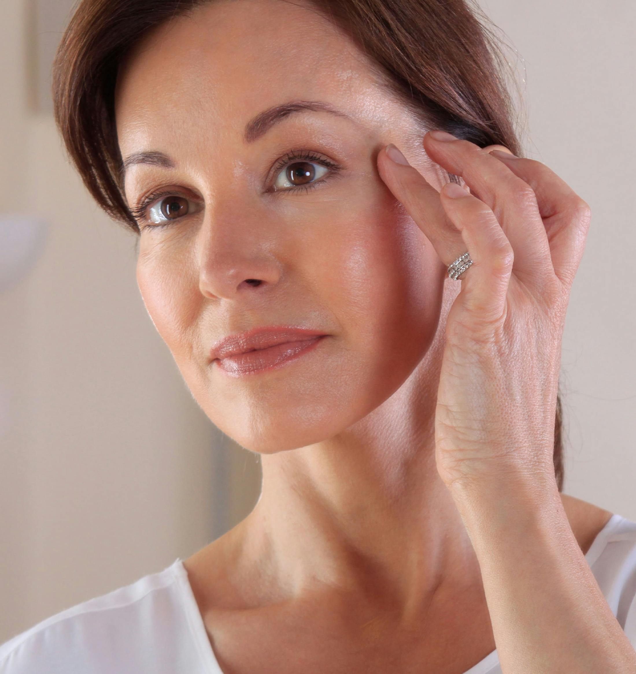 woman looking at her outer corner of her eye in mirror