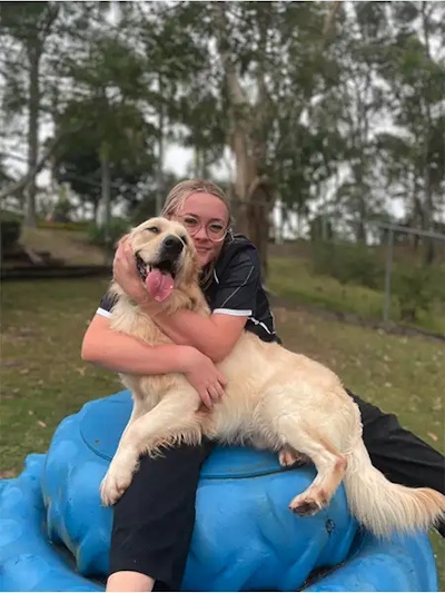 Pet Resorts Australia Samford team member cuddling a happy Golden Retriever during premium pet boarding in a peaceful outdoor setting near Brisbane.