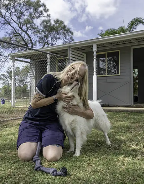 Pet Resorts Australia Townsville team member cuddling a dog outside the Hampton Private Suite – premium dog boarding experience