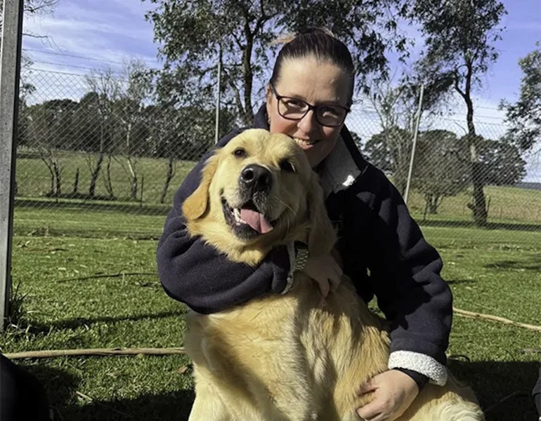 A pet nanny lovingly cuddles a golden retriever dog at the dog boarding facility at southern highlands