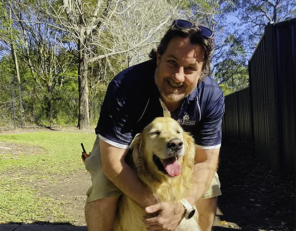 Pet Resort manager cuddles a golden retriever at doggy daycare Terrigal