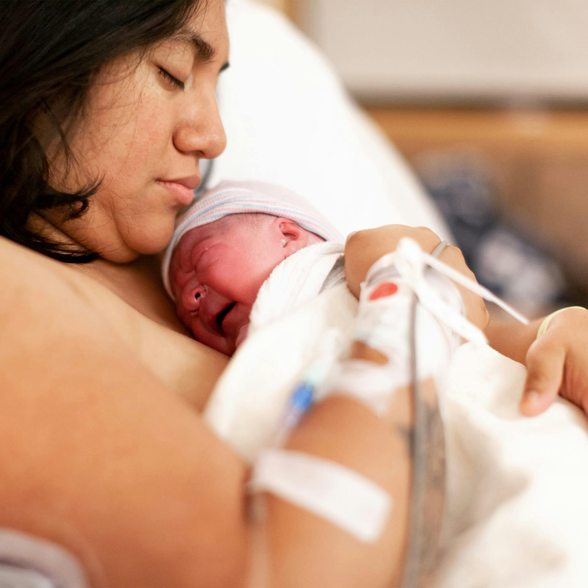 woman in a hospital bed, holding a newborn baby