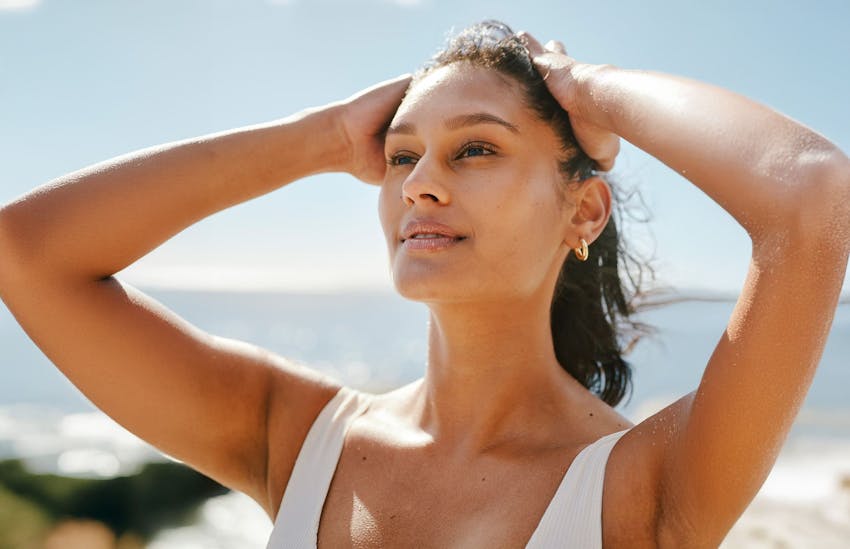 Woman at the beach with hands on head