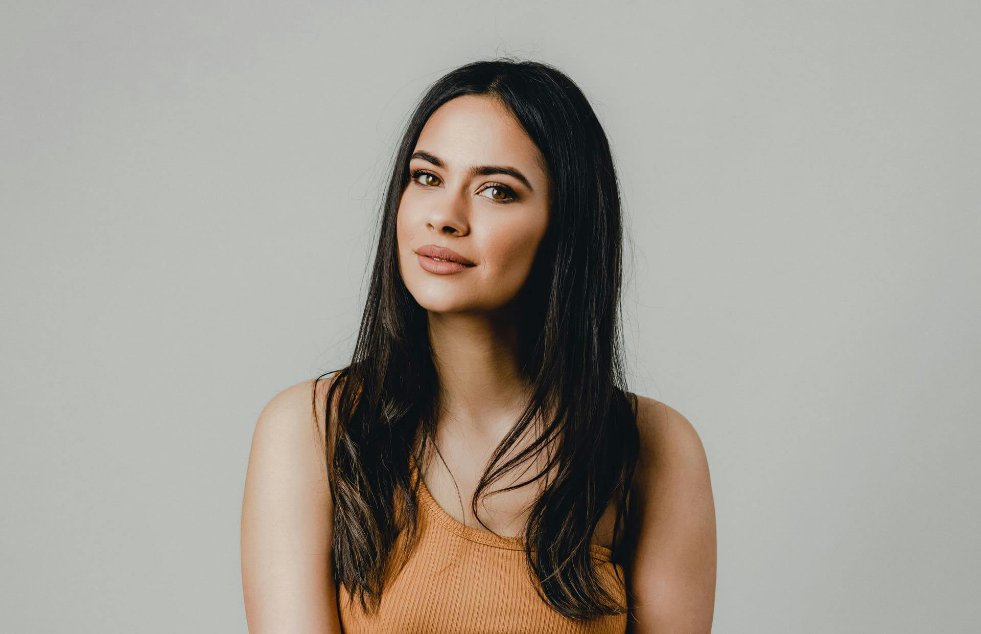 Woman smiling against grey wall