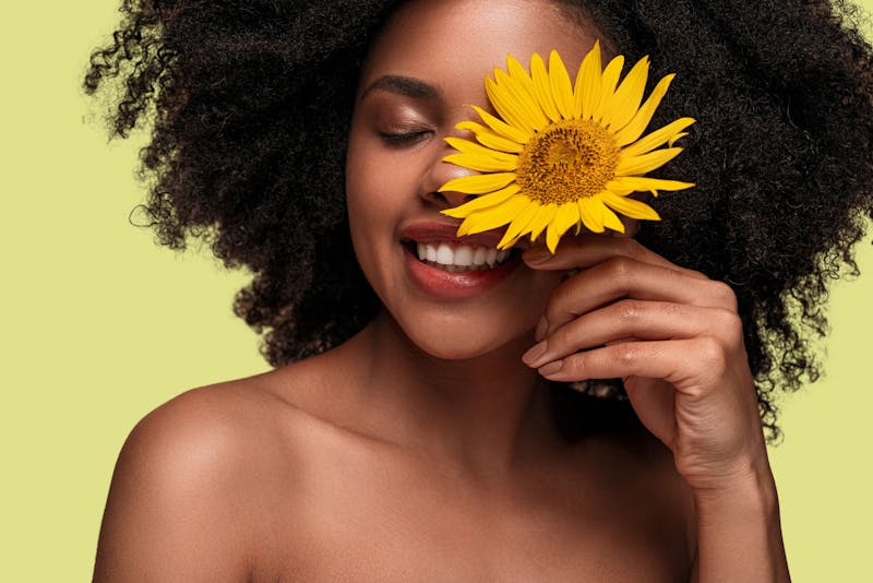 woman holding a sunflower in front of her face