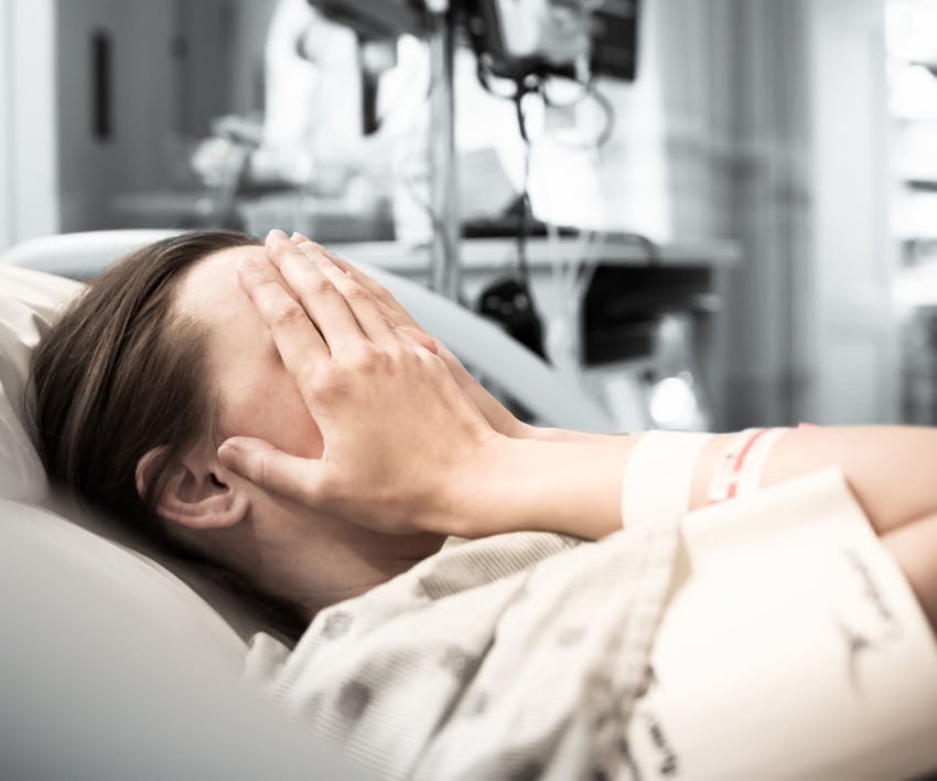 Upset woman in hospital bed with her hands over her face